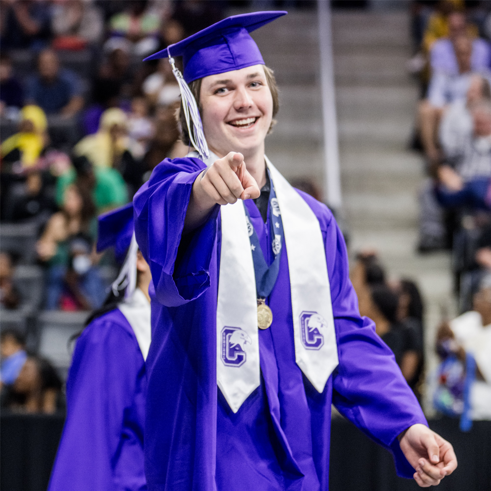  A graduated student smiles and points at the camera